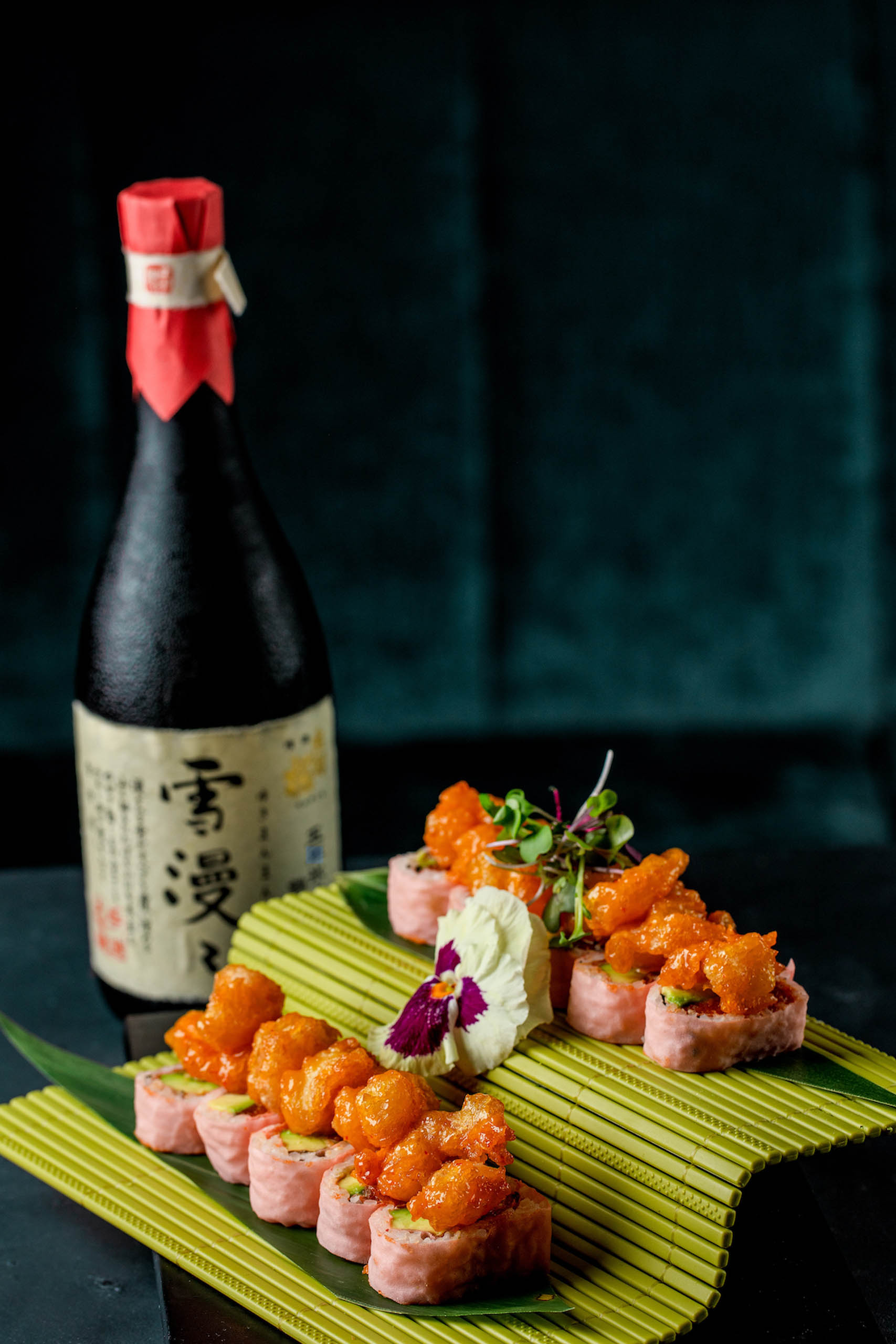 Bottle of sake served with a plate of sushi