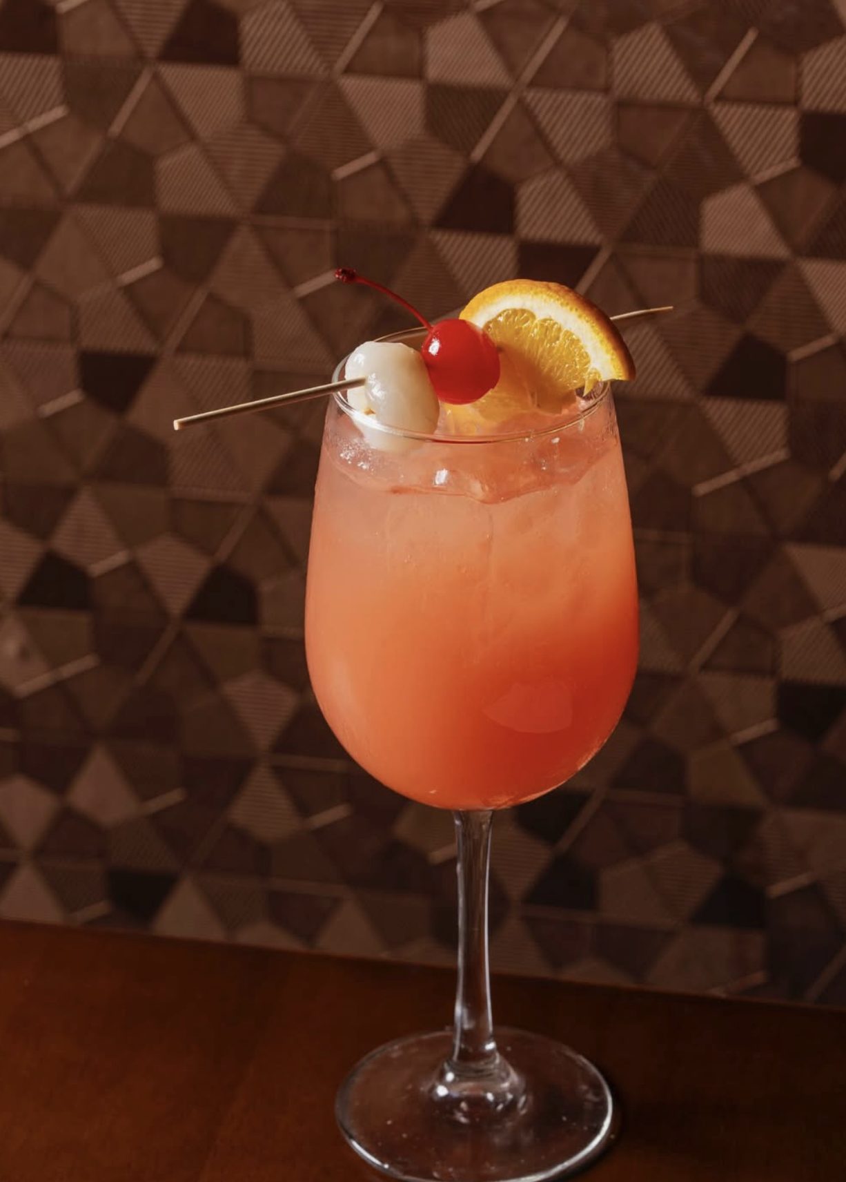 Tropical cocktail garnished with a lychee, cherry, and orange slice