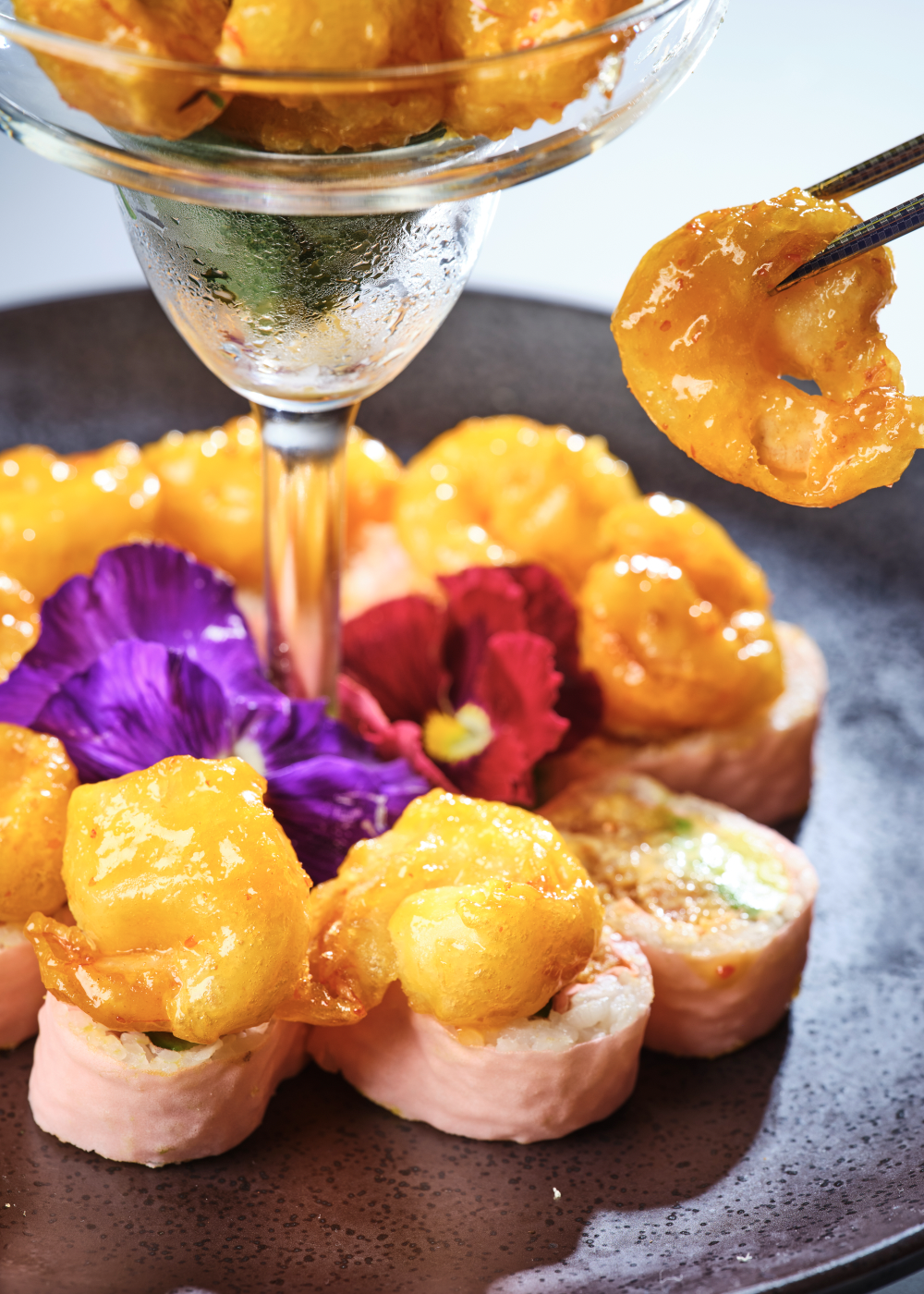 Pink soy paper sushi roll topped with crispy glazed shrimp